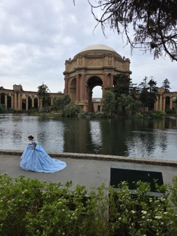 The Palace of Fine Arts architecture during the San Francisco 2026 trek, with a quinceanera in the foreground, girl dressed in blue..